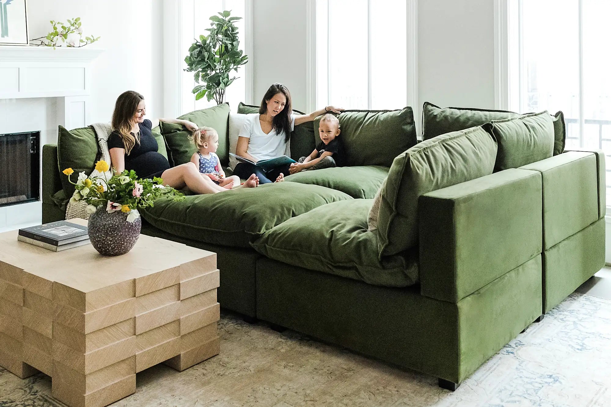 Two women and two toddlers lounging on the Kova Pit in Olive Velvet