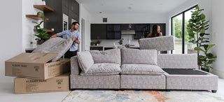 couple unpacking and assembling a grey fabric kova sofa