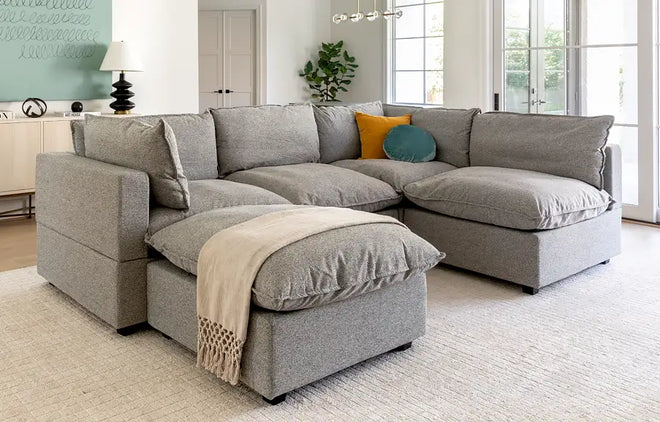 Kova L-Shape and Ottoman in Grey in a living room setting