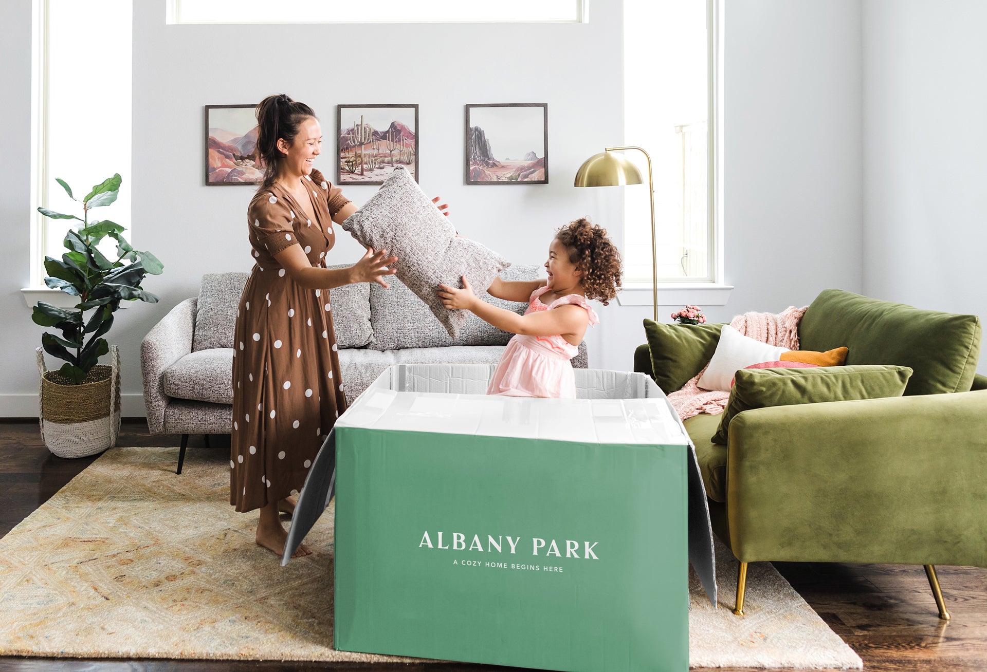 little girl popping out of an Albany Park box handing adult a pillow