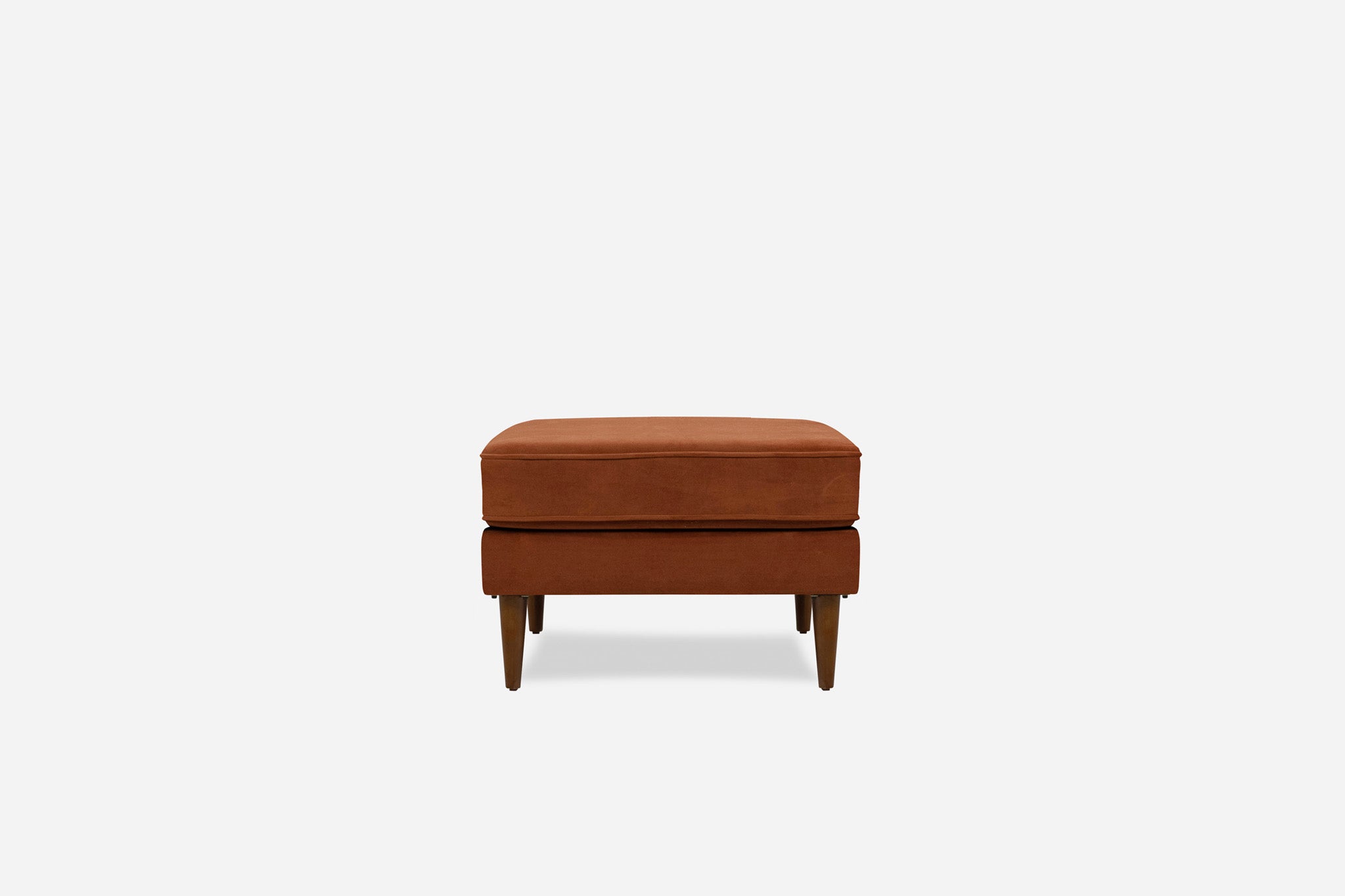 albany ottoman shown in rust velvet with walnut legs