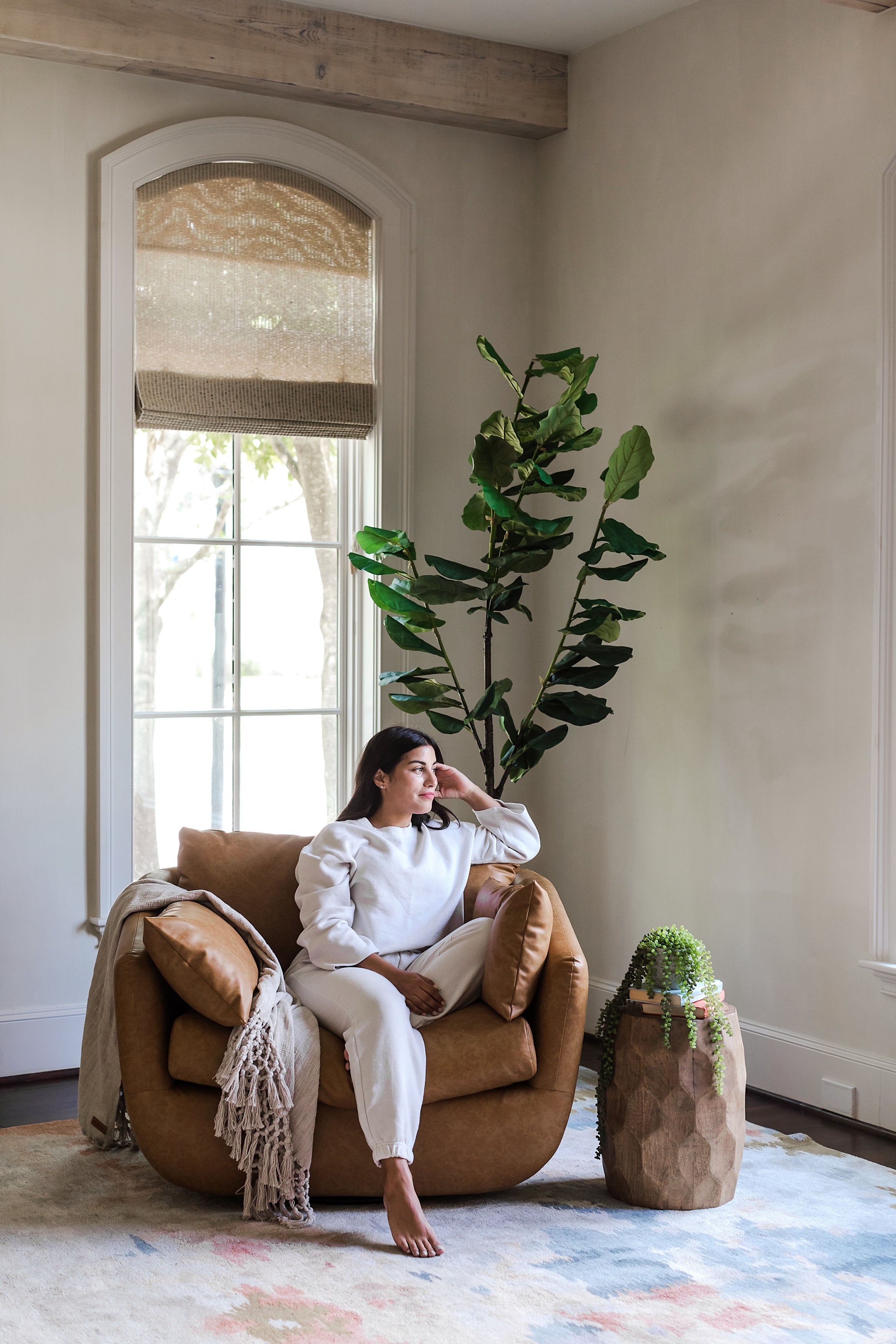 distressed vegan leather | woman seated in park swivel armchair in distressed vegan leather in a living room setting