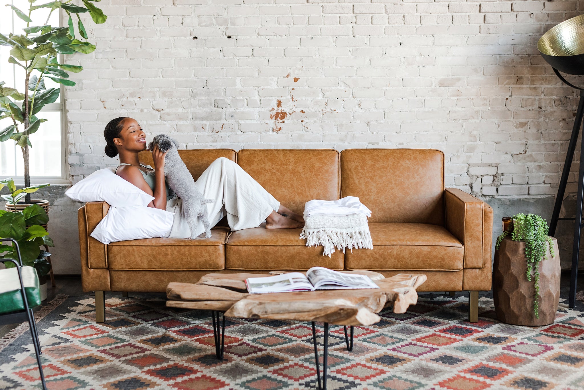 woman seated with her dog in the albany sleeper sofa in vegan leather