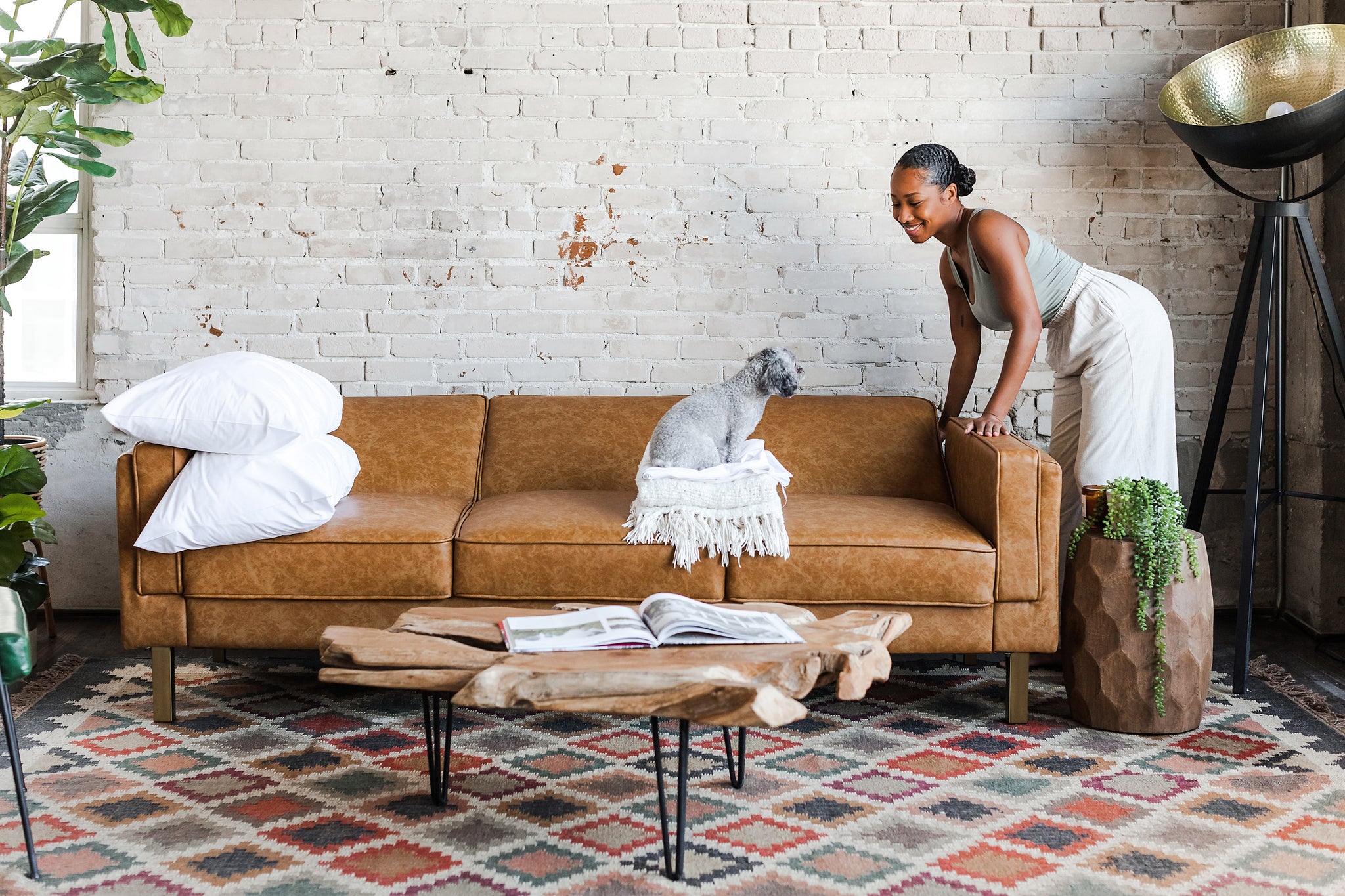 woman opening the albany sleeper sofa in vegan leather with gold legs