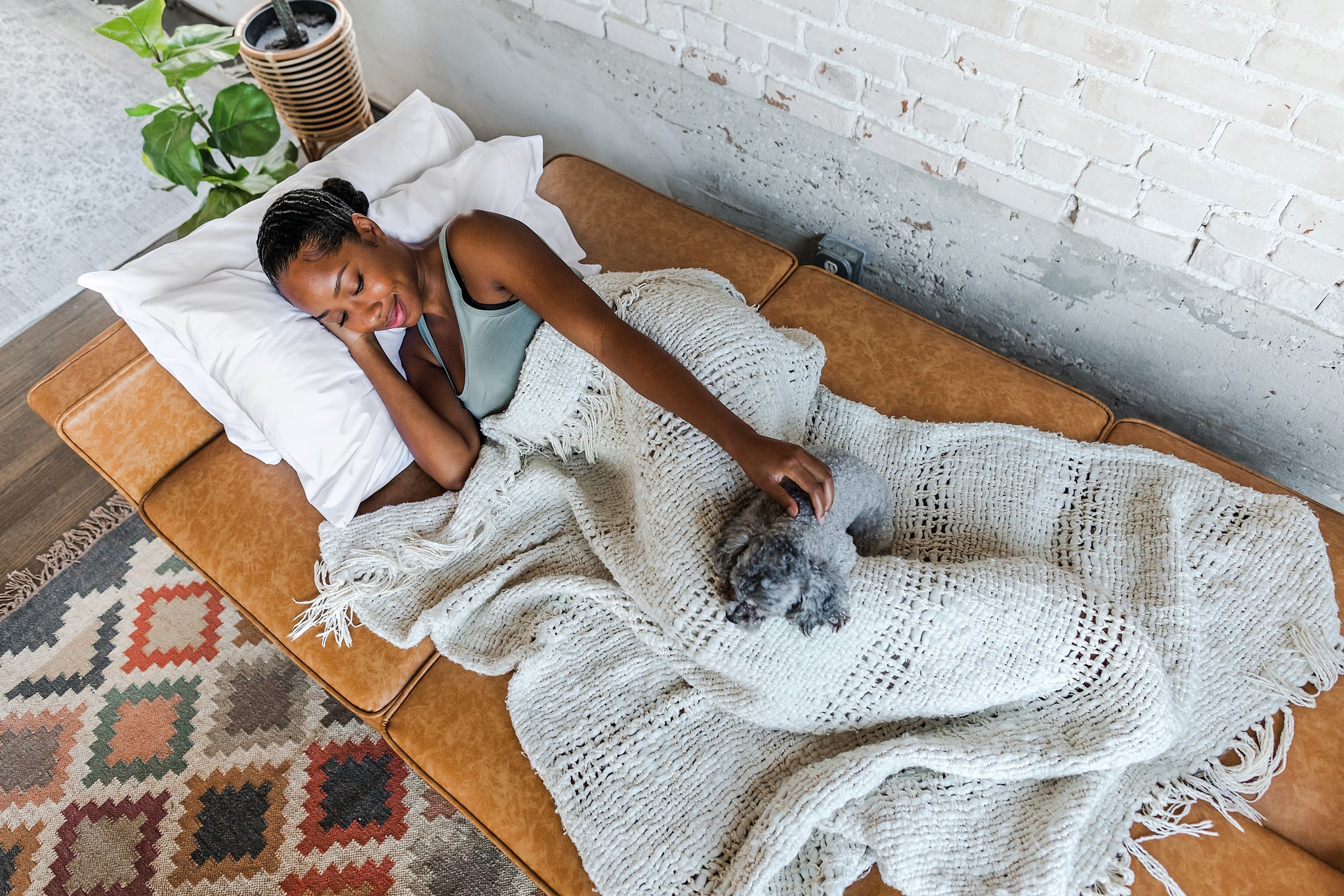 woman laid down with her dog in the albany sleeper sofa in vegan leather