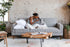 grey fabric walnut | Woman seated with a dog in the Albany sleeper sofa in grey with walnut legs