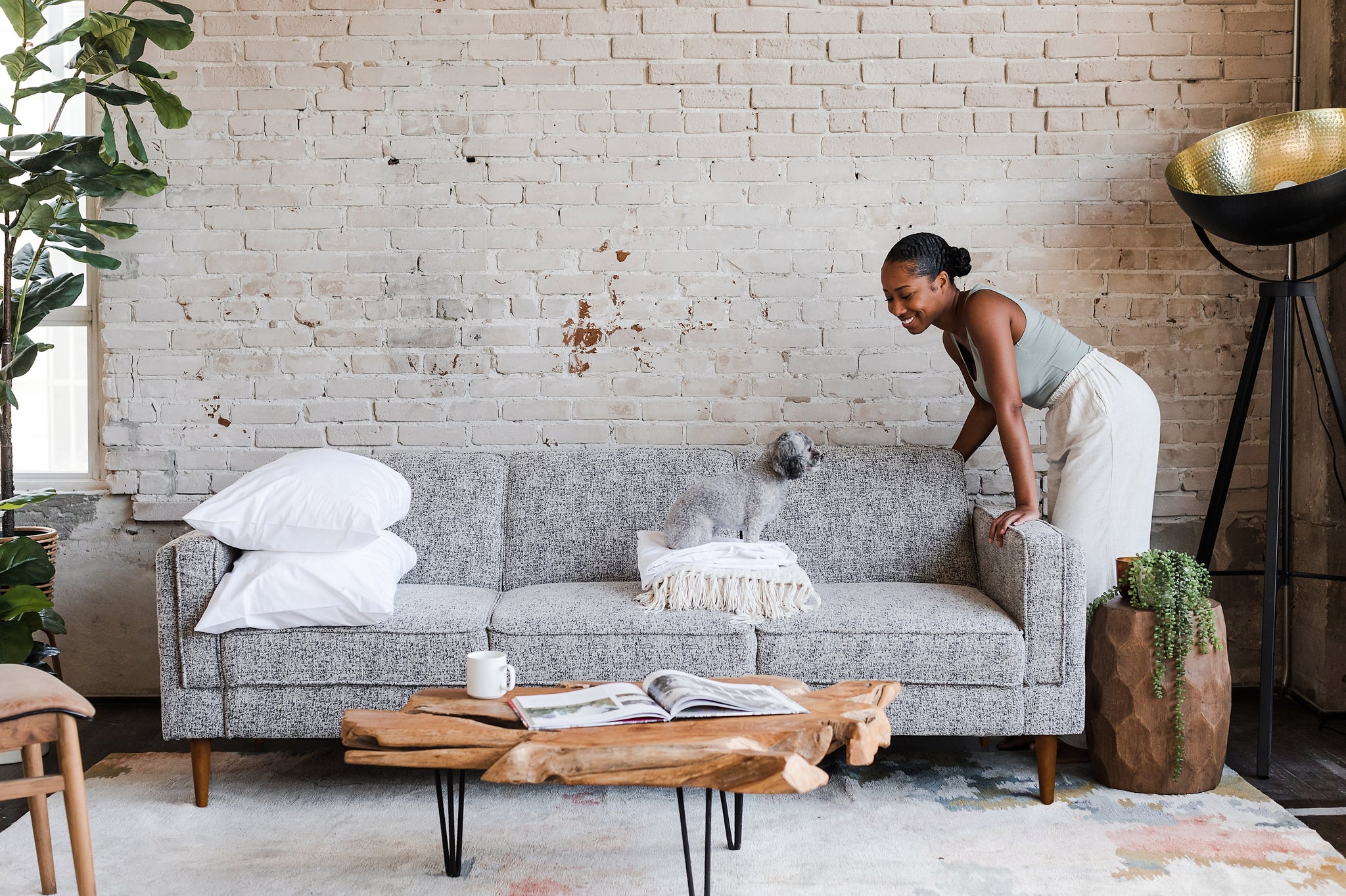 woman opening the albany sleeper sofa in grey fabric with walnut legs