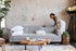 grey fabric walnut | Woman opening the Albany sleeper sofa in grey fabric with walnut legs