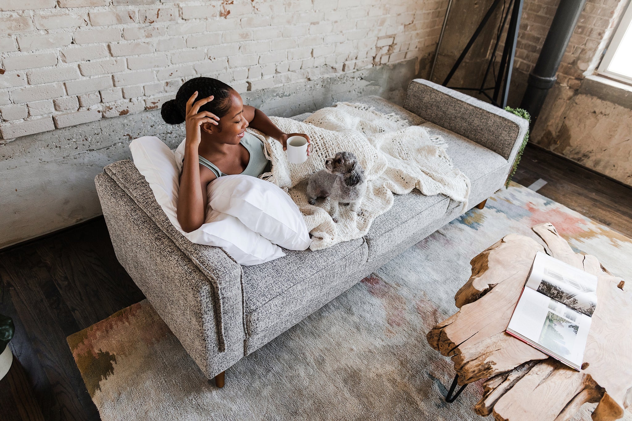 woman lying down in the albany sleeper sofa in grey fabric with walnut legs