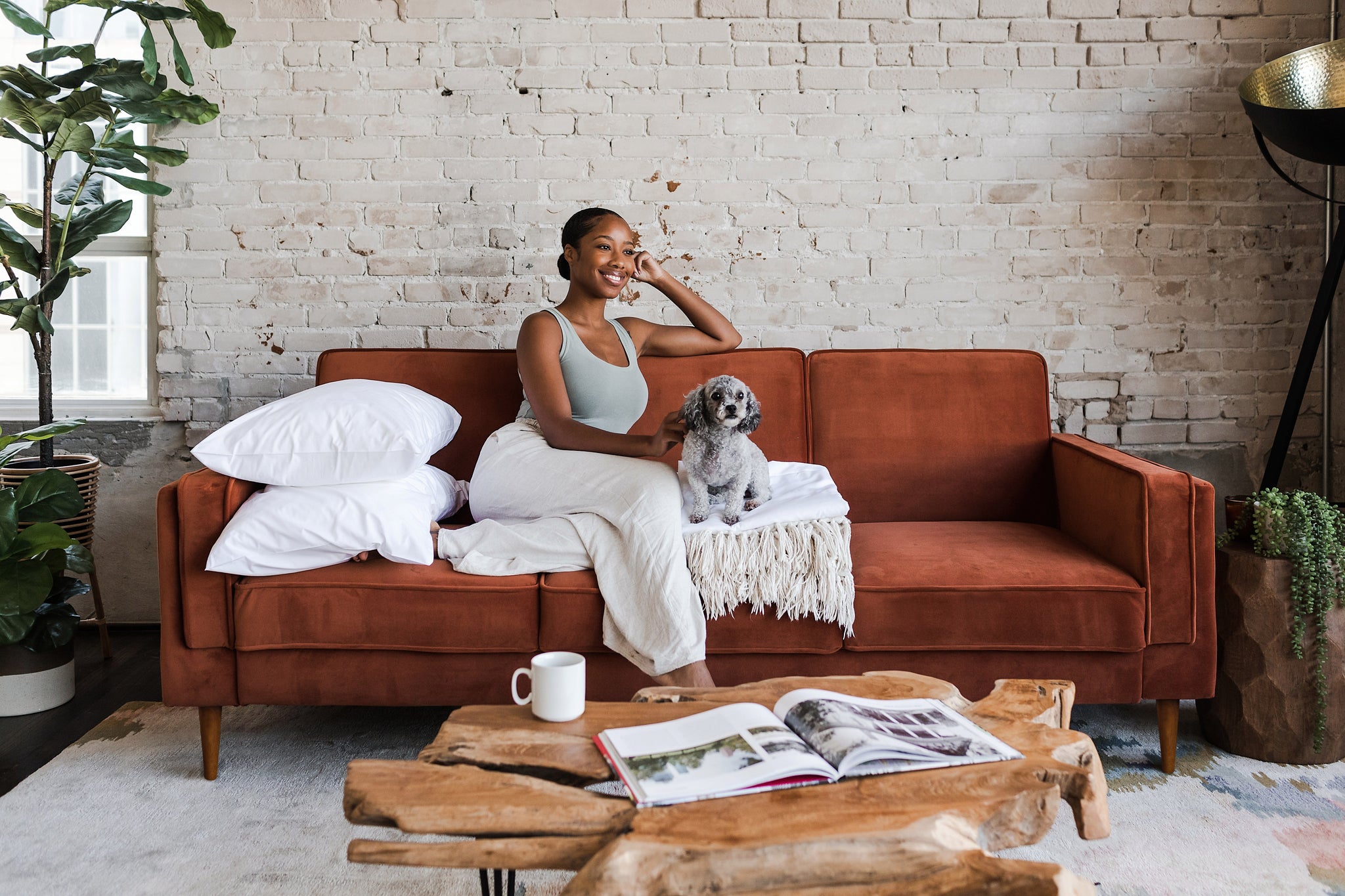 woman seated in the albany sleeper sofa in rust velvet with walnut legs