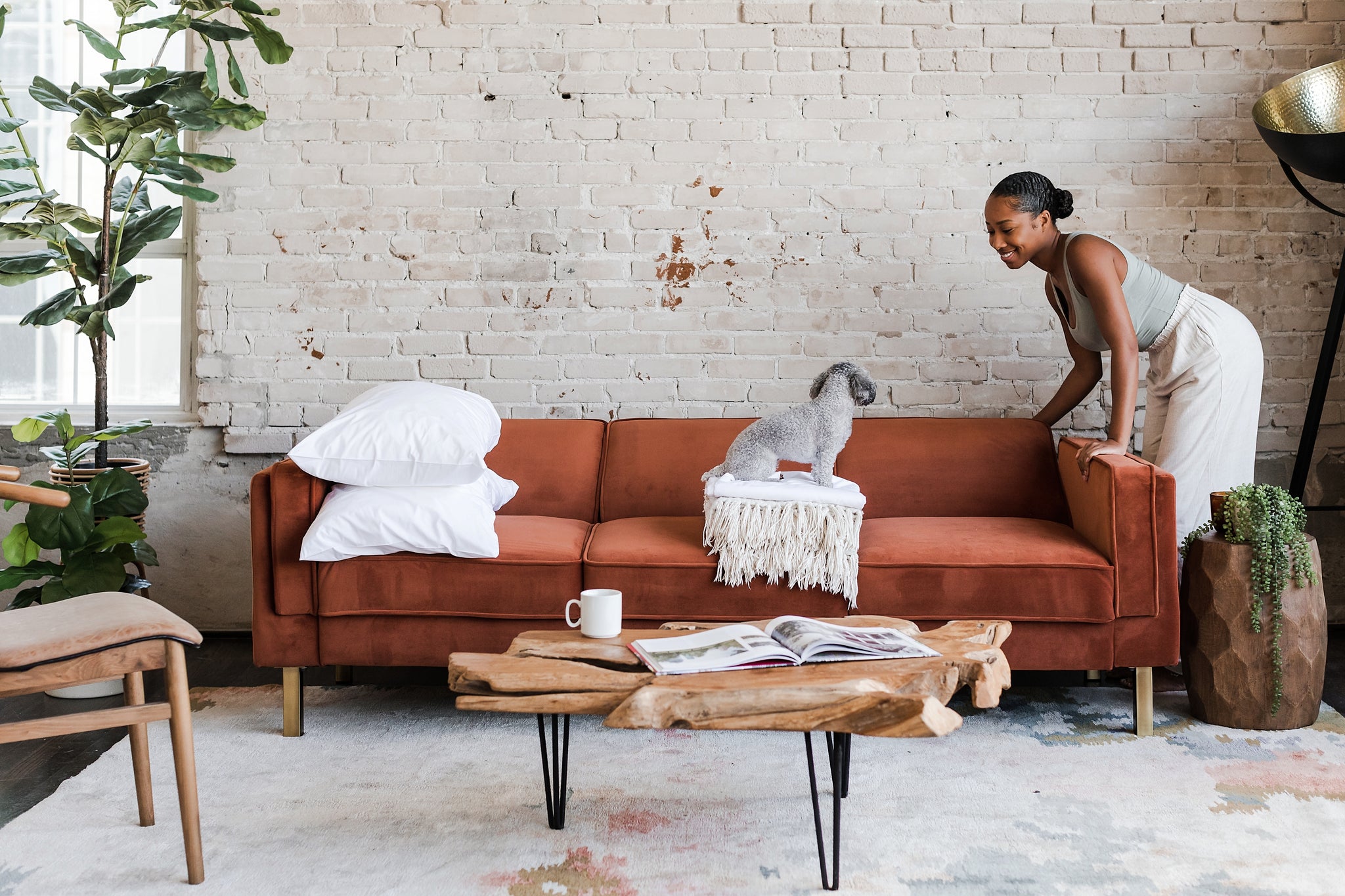 woman opening the albany sleeper sofa in rust velvet with gold legs