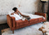 rust velvet walnut | Woman lounging with her dog in the Albany sofa bed in rust velvet with walnut legs