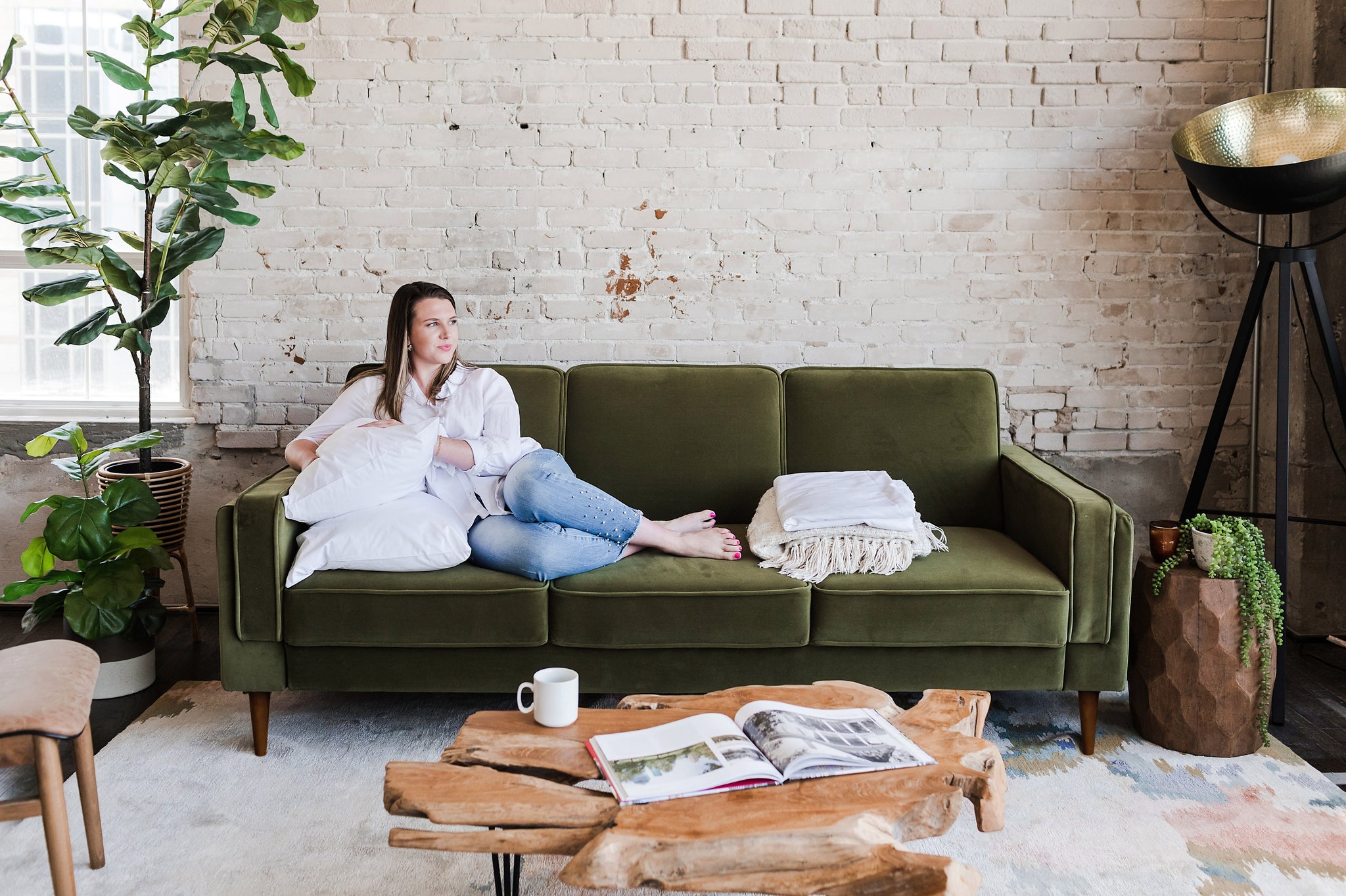 woman seated in the albany sleeper sofa in olive velvet with walnut legs