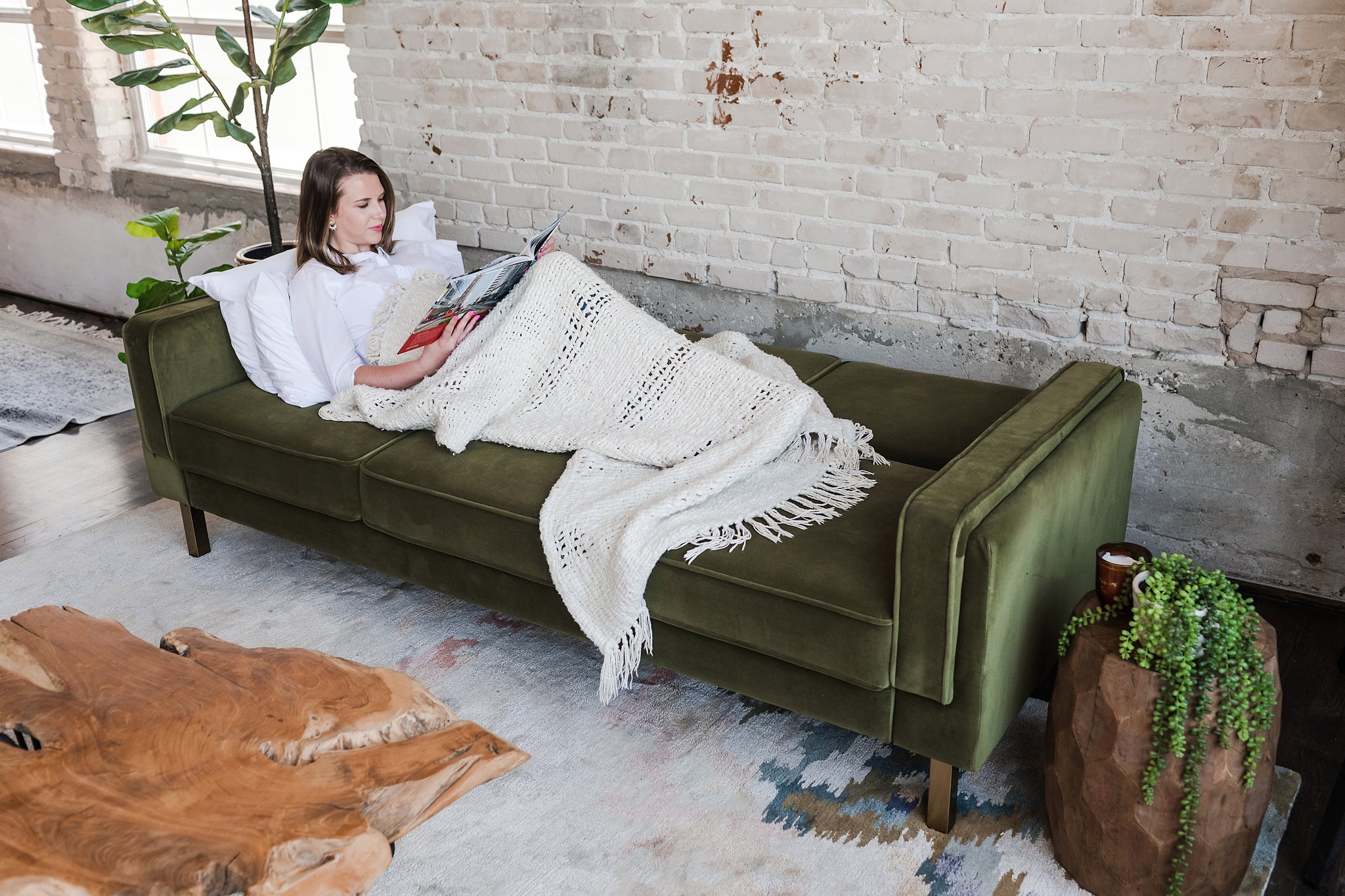 woman lying down in the albany sleeper sofa in olive velvet with gold legs