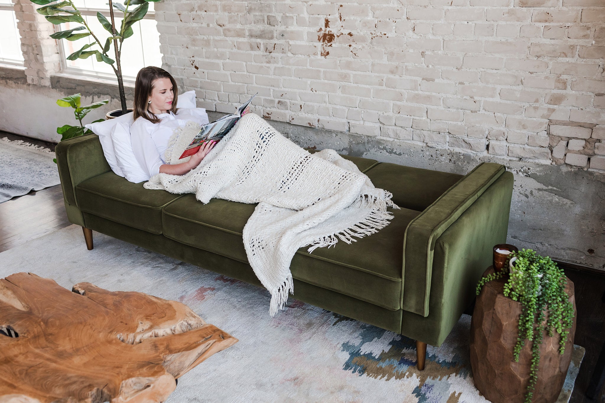 woman lying down in the albany sleeper sofa in olive velvet with walnut legs