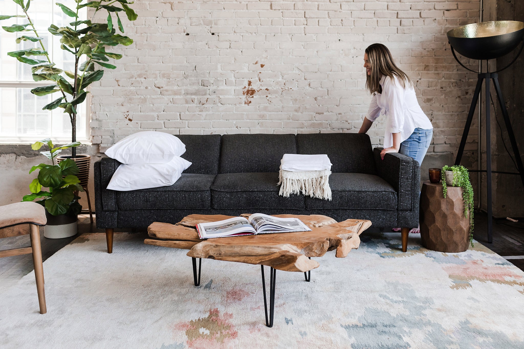 woman opening the albany sleeper sofa in charcoal with walnut legs