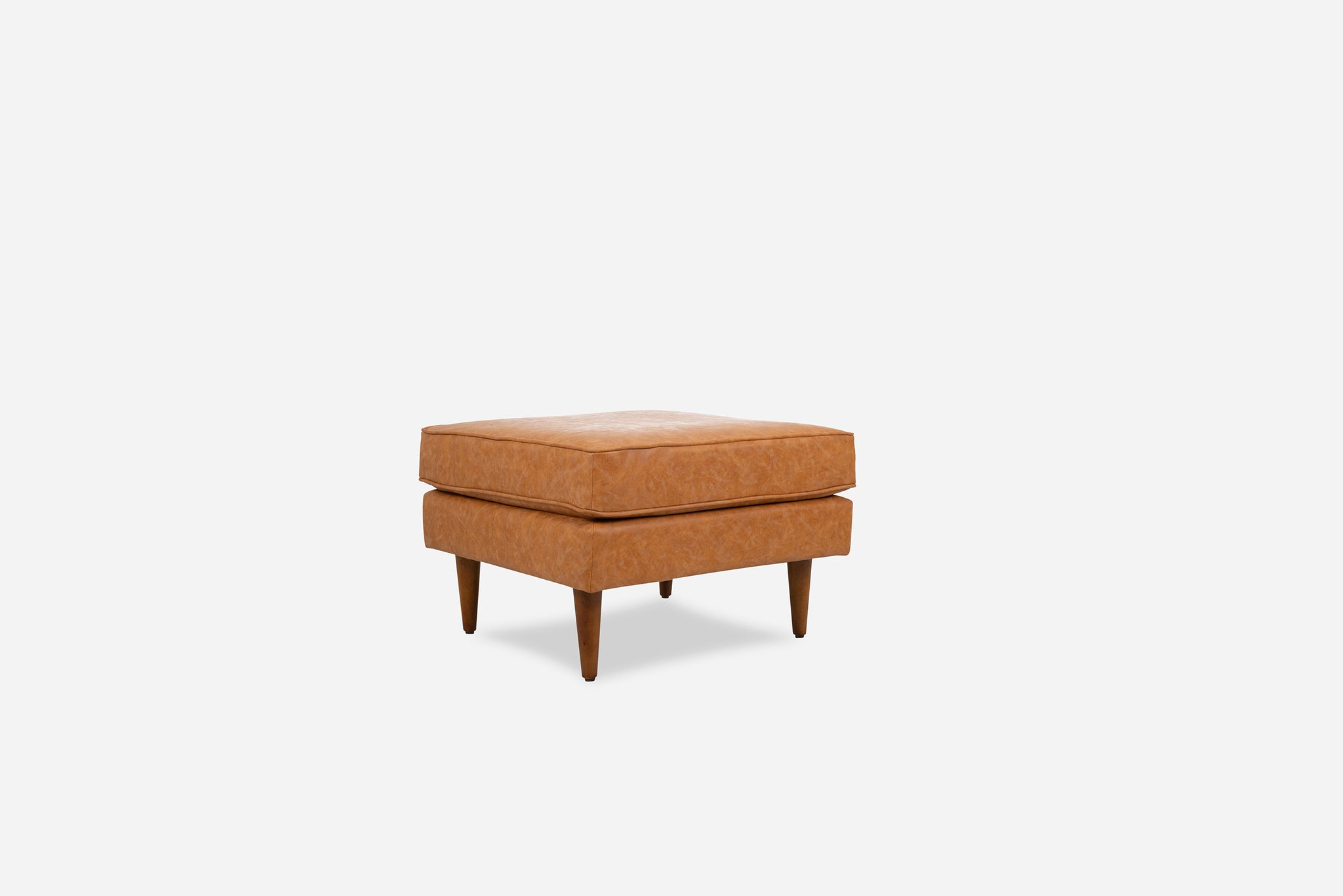albany ottoman shown in distressed vegan leather with walnut legs